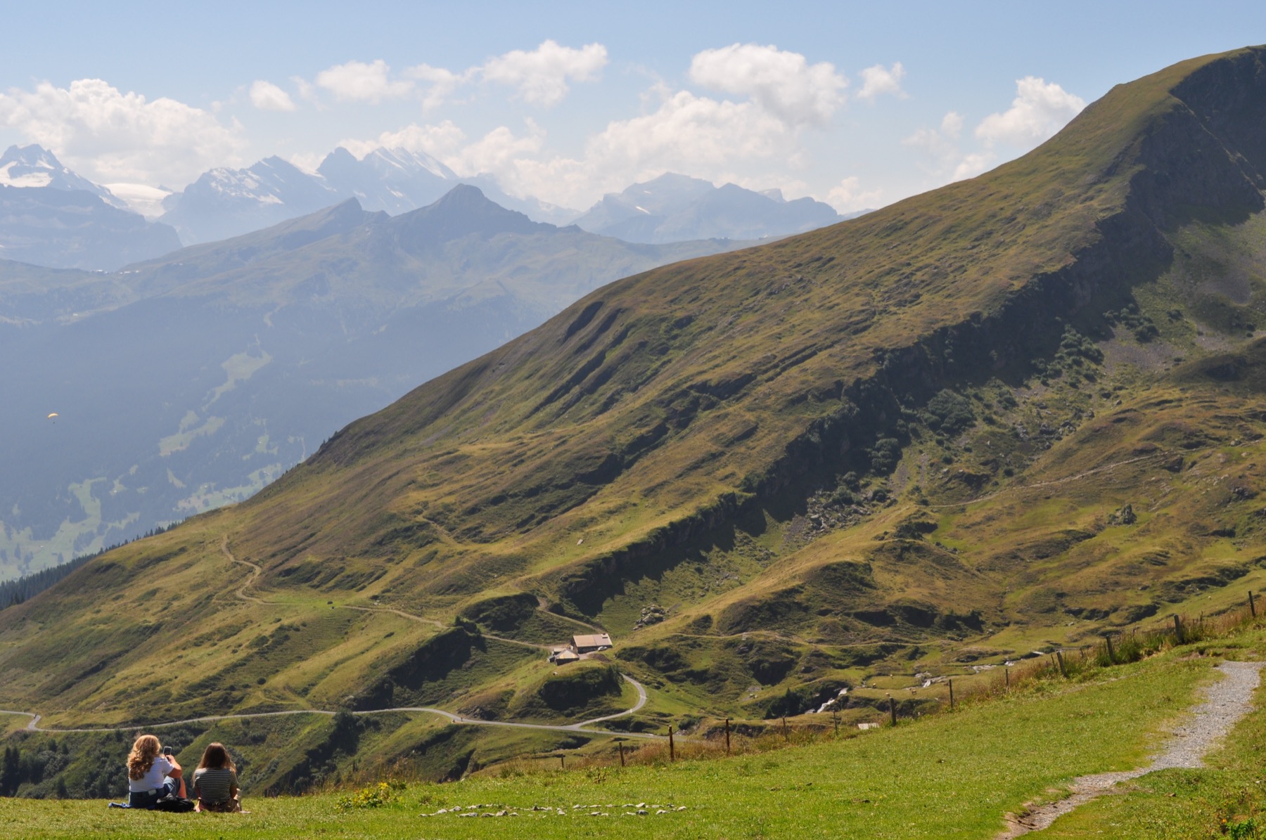 Hikers resting on a grassy ridge overlooking alpine peaks