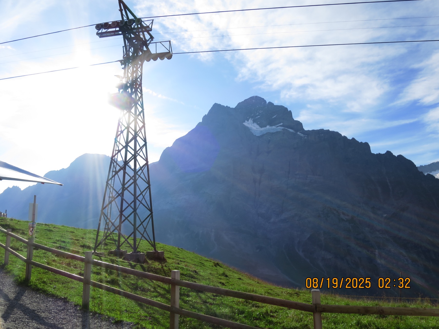 A cable-car tower silhouetted against a backlit mountain ridge