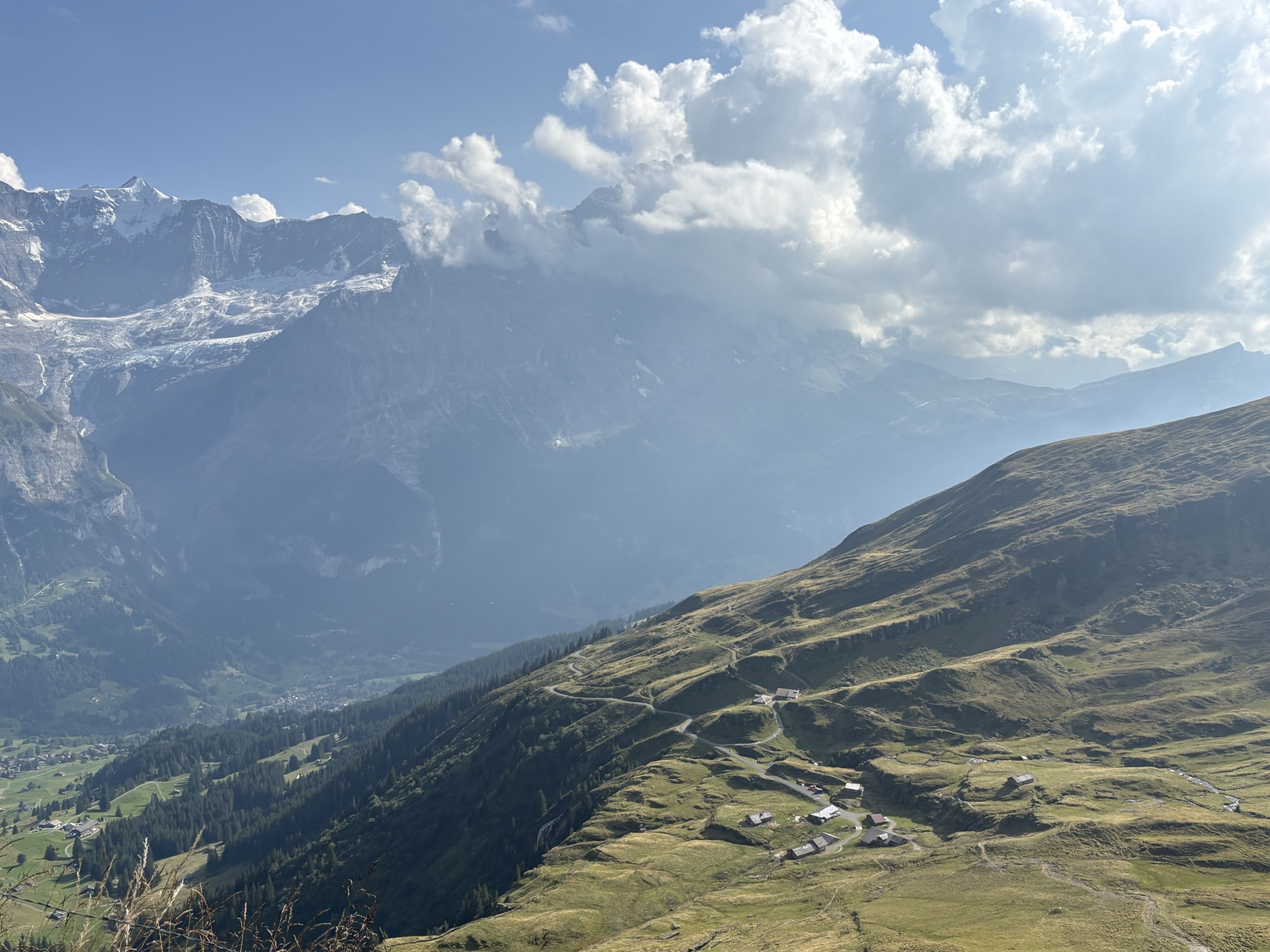 A green valley dotted with chalets beneath the Alps